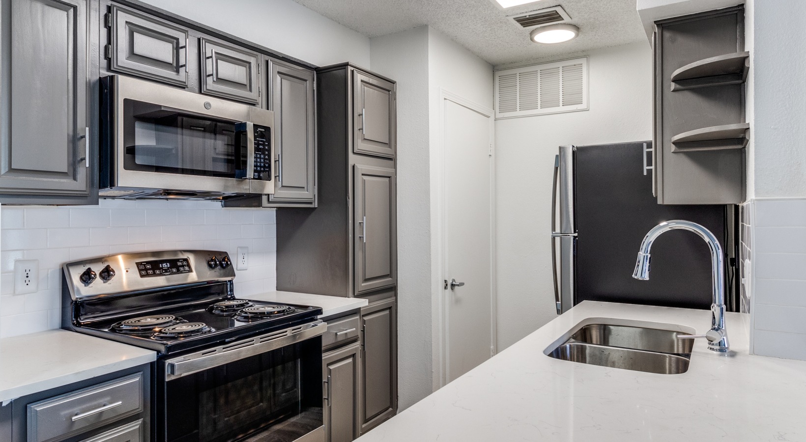 a kitchen with stainless steel appliances and gray cabinets at The  Laney